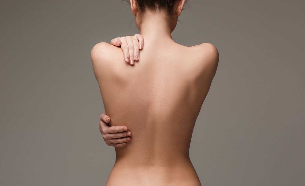 Le dos d'une femme fine avec un fond unis