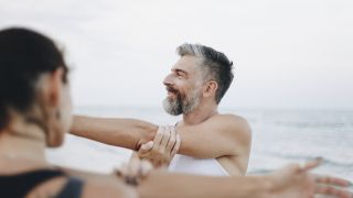 Un homme s'étire avec sa compagne avec la mer en fond