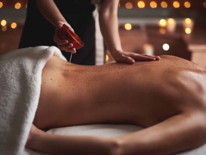 personne réalisant un massage aux huiles essentielles apaissantes sur le dos d'une femme