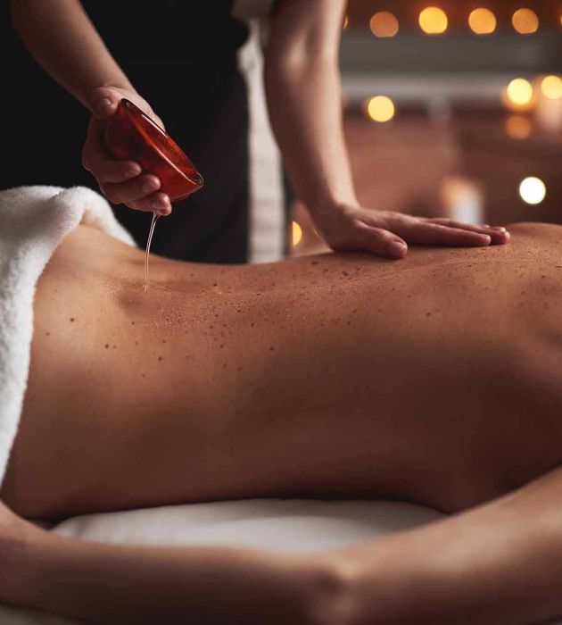 personne réalisant un massage aux huiles essentielles apaissantes sur le dos d'une femme