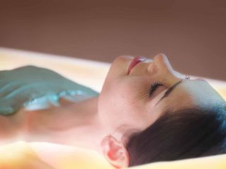 Femme recevant un soin enveloppement de crème d'algues laminaires sur lit hydrosensoriel